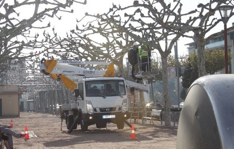 colocando adornos en los arboles con camion cesta